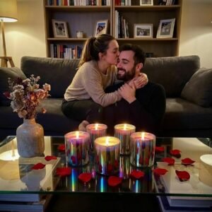 Girl kissing boyfriend on cheek with Lucentius rainbow glass candle lit on table beside them, romantic Valentine's Day moment